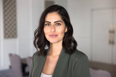 Pozitif güzel İspanyol iş kadını ofiste poz veriyor, kameraya bakıyor. Başarılı genç Latin kadın şirket lideri, profesyonel portre sahibi.