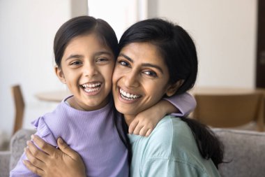 Neşeli genç Hintli anne ve sevimli kız çocuğu sevgiyle sarılıyorlar, çocukluktan zevk alıyorlar, yakınlık, annelik, yüz teması ile poz veriyorlar, kameraya bakıyorlar, gülüyorlar.