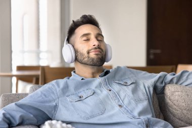 Kaygısız, büyük kulaklıklı, beyaz kulaklıklı, dinlenen, dinlenme odasında meditasyon yapan, gözleri kapalı, temiz hava soluyan, favori melodilerin, şarkıların tadını çıkaran bir İspanyol.