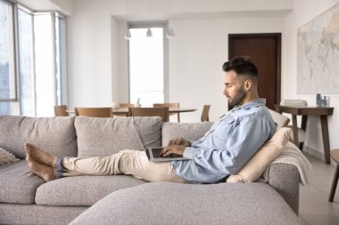 Odaklanmış, rahat bir koltukta dinlenen, dizüstü bilgisayarda yazan, medya web servisini kullanan, interneti karıştıran genç İspanyol bir adam. Evden proje üzerinde çalışan serbest çalışan, konforun keyfini çıkaran