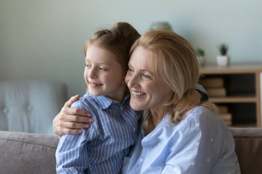 Mutlu olgun bir büyükanne kucağında tatlı bir torun, kucağında çocuk, koltukta oturuyor, dişlek tebessümleriyle başka tarafa bakıyor. Büyükanneni ve torununu sevmek, evde vakit geçirmek.