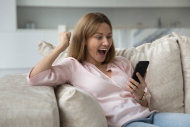 Neşeli, heyecanlı cep telefonu kullanıcısı kadın ekranda, kazanan eli yapıyor, başarıyı kutluyor, sürpriz, başarıyor, şans, sevinç çığlıkları, gülüyor, sevinçle seviniyor.