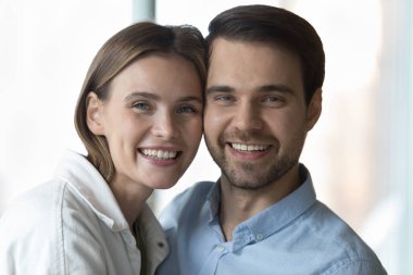 Mutlu genç koca ve güzel eş dişlek gülümsemeyle kameraya bakıyor, gülüyor, yanaklarına dokunarak sarılıyor. Birbirini seven, sağlıklı ve romantik ilişkiler içinde pozitif çiftler. Yakın portre.