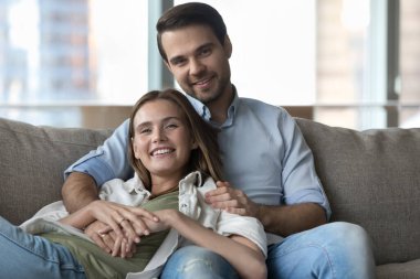 Neşeli, mutlu, çekici, genç bir karı koca, birbirine aşık bir ev portresi. Romantik bir ilişkiden hoşlanan mutlu bir çift, evde dinleniyor, güvenle sarılıyor, kameraya bakıyor.