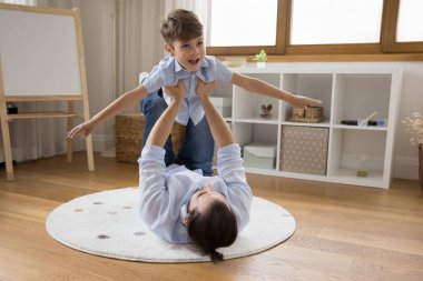 Güçlü, şefkatli, genç bir baba kucağında çocuk, heyecanlı oğlunu kaldırıyor ve uçuyor. Baba ve çocuk eğitimi, oyun odasında ısıtmalı zeminde egzersiz. Aile etkinliği