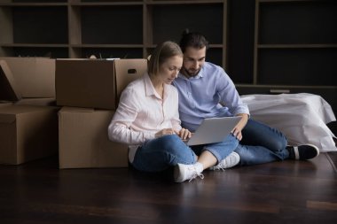 Evli çift taşınma gününde dizüstü bilgisayar alıp sipariş veriyorlar. E-ticaret hizmetleri müşterileri mobilyaları, oturma odası iç tasarım fikirlerini internetten seçer. Taşınma, e-servis müşterileri konsepti