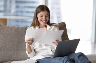 Üniversiteden iyi haberlerle gelen mutlu, genç bir kız öğrenci laptopta gazete okuyor, gülümsüyor, gülüyor. İş kadını belge okuyor, yüksek iş sonuçlarına gülümsüyor, satış raporları