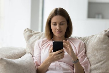 Odaklanmış 30 'lu yaşlardaki akıllı telefon kullanıcısı sohbet ediyor, mesaj yazıyor, ekommerce uygulamasını kullanıyor, alışveriş yapıyor, sanal servisle cep telefonundan online alışveriş yapıyor. İnternet iletişimi