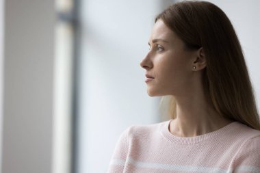 Yandan bakan üzgün genç kadın evde yalnız başına duruyor, bayan ya da bekliyor ya da başka biri, hayatla baş etmek yalnızlık çekiyor, boşanma ya da evlilikten geçiyor.