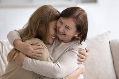 Mutlu, yaşlı, emekli anne, neşeli yetişkin çocuğa hayranlıkla sarılıyor, sevgi, sıcaklık, sıkılaştıran kız çocuğu, gülümsüyor, gülüyor, şefkat duyuyor, şefkat gösteriyor, annelikten keyif alıyor, anneler günü.