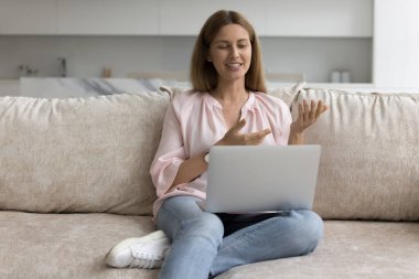 30 'lu yaşlardaki çekici dizüstü bilgisayar kullanıcısı kadın. Kanepede dinleniyor, video görüşmesinde konuşuyor, bilgisayar ekranında konuşuyor, webcam' de konuşuyor, internette sohbet ediyor. Blogger kayıt paylaşımı. İnternet iletişimi