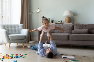 Güçlü bir baba heyecanlı, neşeli bir kızı havaya kaldırıyor, uçak oyunu oynuyor, ısınma zemininde egzersiz yapıyor, çocukla akroyoga yapıyor, eğleniyor. Babalık, aile kavramı
