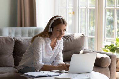 Kablosuz kulaklık takmış, evden ders çalışan mutlu nişanlı öğrenci kadın. Çevrimiçi sınıfa katılıp, bilgisayardan video görüşmesi yapıyorum. Öğretmen ve blog yazarı webinar veriyor, atölye