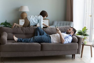 Rahat baba kanepede dinleniyor, cep telefonu tutuyor, sanal oyun oynuyor, internetten alışveriş yapıyor, ekommerce uygulamasını kullanıyor, servis yapıyor, oğlunu evde izliyor. İletişim, babalık kavramı