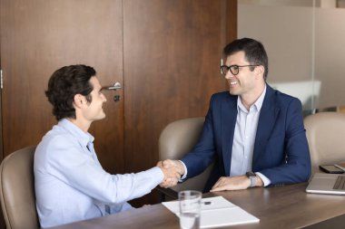 Mutlu erkek iş ortakları pazarlıktan sonra tokalaşıyor, istişare masasında toplanıyor gülümsüyor, gülüyor, ortaklığı tartışıyor, anlaşmaya varıyor.