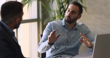 Kendinden emin Latin proje yöneticisi erkek iş arkadaşıyla konuşuyor, iş stratejisini, satış raporunu, pazarlama planını ortağa, müşteriye sunuyor. Girişimciler ofiste dizüstü bilgisayarla konuşuyorlar