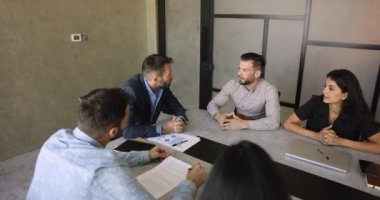 Erkek patron, şirket toplantısında en mutlu yöneticiyle konuşuyor. Çalışanlara el sıkışıyor. Saygı gösteriyor, iyi iş çıkardığı için takdir ediliyor. İş ortakları konferans masasında el sıkışıyor.