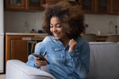 Heyecanlı neşeli kız Z-Afrikalı cep telefonu kullanıyor, şaşırtıcı iyi haberler alıyor, ekrana bakıyor, gülüyor, zaferi kutluyor, başarı, şans, başarı, başarı, iyi sonuç.