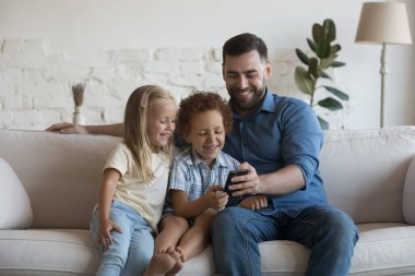 Mutlu milenyum babaları, neşeli küçük kız ve oğullarına cep telefonlarında online nakliye uygulaması kullanmayı öğretiyor, selfie çekiyor, video görüşmesi yapıyor, internette oyun oynuyor, kanepede dinleniyor.