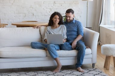 Mutlu nişanlı milenyum çifti evlerinde kanepede oturmuş dizüstü bilgisayarlarını kucağında tutuyorlar, bilgisayarlarını paylaşıyorlar online alışveriş uygulamalarını, internet servislerini kullanıyorlar, konuşuyorlar, sohbet ediyorlar, gülümsüyorlar, sarılıyorlar. Tam uzunluk