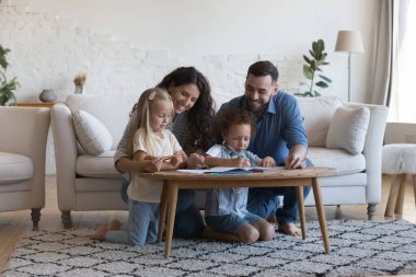 Anne ve baba, küçük kardeş çocukların renkli kalemler çizmesine, yaratıcı hobilerinin keyfini çıkarmalarına, birlikte vakit geçirmelerine, sıcak halı döşemelerine oturmalarına yardım ediyor. Aile aktiviteleri konsepti