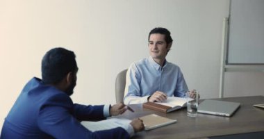 Sözleşme, anlaşma, şirket başarısı, proje işbirliği konularında ciddi anlamda başarılı olan çok ırklı genç erkek iş ortakları. İspanyol yöneticiler toplantı masasında iş arkadaşlarıyla konuşuyor.