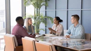 Çeşitli Afrikalı ve Kafkas iş arkadaşları proje yönetimi üzerine beyin fırtınası yapıyorlar toplantı masasında konuşuyorlar, iş iletişimini tartışıyorlar. Sancak vuruşu