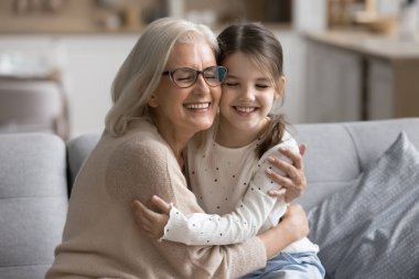 Sevgi dolu büyükanne ve torun arasında geçen, gözleri kapalı kanepede oturan, derin duygusal bağın ve koşulsuz sevginin tadını çıkaran bir an. Aile bağları, nesiller arası bağlantı