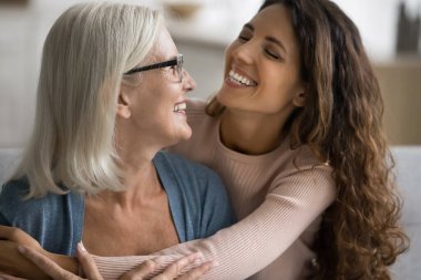 Büyük anne ve sevgi dolu kızı arasında sevgi dolu ve neşeli bir an var. Yaklaş. Evde sarılan çok nesilli akrabaları var. Yakınlık ve koşulsuz sevgi gösteriyorlar. Aile bağları