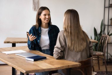 İki genç iş kadını, dost canlısı takım arkadaşları, ofiste yapılan brifing sırasında hoş, olumlu sohbetlere öncülük eden meslektaşlar, yaratıcı vizyon, fikir ve çözümler alışverişi, gülme, konuşmaktan keyif alma,