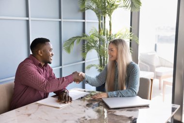 Mutlu çoklu etnik çeşitlilikte iki meslektaşın müzakere masalarının üzerinde el sıkışıyor, iş görüşmeleri, gülüşmeler, anlaşma sağlanıyor, ortaklık başlıyor, kapanış anlaşması yapılıyor, danışma için teşekkür ediliyor.