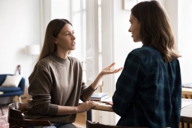 Genç bir kadın, görev sırasında güzel bayan meslektaşlarına profesyonel tavsiyelerde bulunuyor, masada oturuyor, gayri resmi sohbetlere öncülük ediyor, görüşlerini paylaşıyor, fikirlerini paylaşıyor ve etkili çözümler sunuyor.