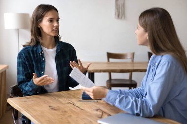 Sohbete katılan genç bayan aday, el hareketlerini kullanarak eğitim, mesleki beceriler ve bilgiyle ilgili soruları cevaplarken kendinden emin hisset. Resmi toplantı, işe alım, şirket kadrosu.