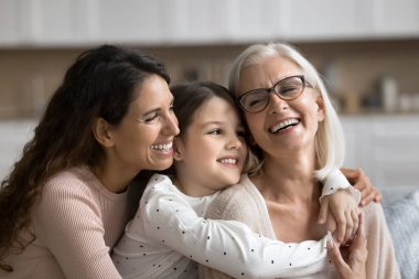 Üç kuşak boyunca kucaklaşan, gülümseyen, birlikte hoş vakit geçiren, yaşam etkinliğini kutlayan, evde mutlu anneler günü kutlayan, kapatan kadınlar. Aile birliği, sevgi, farklı nesiller arasındaki derin bağ.