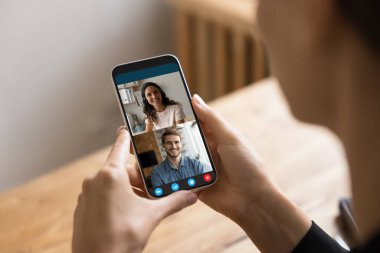 Kadın akıllı telefonu tutar, mobil uygulama kullanarak video çağrısına katılır, kadın omzunun üzerinden ekranı kapatır. Bir grup iş adamı ya da arkadaş sohbete katıldı. Dijital iletişim