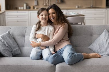 Gülen bir kadın küçük sevimli kızına sarılıyor, eğleniyor, birlikte hoş, paha biçilemez bir oturma odasında eğleniyor. Mutlu annelik, yetiştirme ve yetiştirme çocukları, aile sevgisi ve bağları