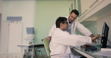 İki olgun 40 'lı yaşlardaki doktor ultrason odasında bilgisayar ekranındaki ultrasonografi görüntülerine bakıp hasta sağlığı durumu ve tedavi planı hakkında fikir alışverişinde bulunuyor.