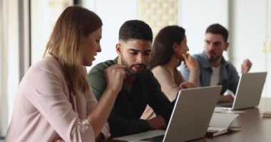 Çeşitli erkek ve kadın iş arkadaşları dizüstü bilgisayarda online projeyi tartışıyor, ortak çalışma masasında konuşuyor, ekranı işaret ediyorlar. Bilgisayarda danışman eğitimi stajyeri, görevi açıklıyor.
