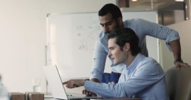 Çevrimiçi başvuru, web sitesi, internet içeriği üzerinde birlikte çalışan iki genç çoklu etnik girişimci yönetici, iş yerindeki dizüstü bilgisayarın başında oturuyor, ekranı gösteriyor, konuşuyor, işi tartışıyorlar.
