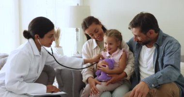Hintli kadın çocuk doktoru, çocuğu muayene eden, kız nefesini ve kalp atışlarını steteskopla dinleyen, küçük bir hastayı ve birkaç ebeveyni evde ziyaret eden, sağlık kontrolü için buluşan,