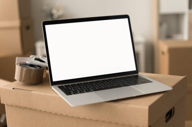 Elektronik ticaret deposundaki karton kutuya yerleştirilmiş boş ekranlı dizüstü bilgisayarın yakın çekim görüntüsü. Nakliye, lojistik uygulama arayüzü ve iş uygulaması için kopyalama alanı olan bilgisayar ekranı