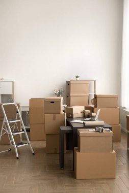 Bilgisayar, merdiven ve nakliye kutularıyla lojistik müdürü çalışma masası. İnternet deposunda kimse yok, paketler istiflenmiş, ulaşım için paketler var.