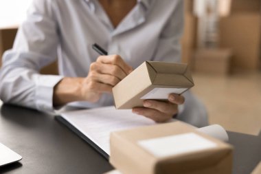 İnternet mağazası sahibinin kadın elleri, ecommerce depolama çalışanı kağıt ambalajlara lojistik notlar yazan, karton kutuyu nakliyeye hazırlayan, müşterilerin işlem sırasını hazırlayan kadın.