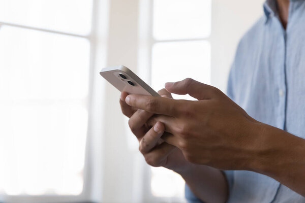 Male hands holds smart phone, close up cropped shot, use new mobile application at workplace, spend time in social media, on internet. Modern technology, connection, communication, business concept