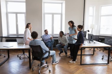 Grup toplantısı sırasında altı dost canlısı çoklu etnik ofis çalışanı konuşuyor, işe olumlu esprilerle başlıyorlar mutlu görünüyorlar, şakalar modern çalışma alanında toplanıyor. Brifing, iş akışı, takım oluşturma kavramı