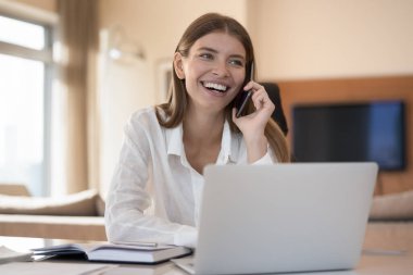 Gülümseyen 25 'li kadınlar dizüstü bilgisayarlarıyla masaya oturur ve akıllı telefonlarıyla konuşur, arkadaşlarıyla gevezelik eder, resmi hoş sohbetler yapar, telekomünikasyon cep telefonu operatörü kullanarak müşterilerine hizmet sunar.