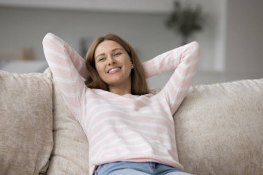 Mutlu kadın rahat koltuklarda dinleniyor. Huzurlu kadın ellerini başının arkasına koyup tek başına dinleniyor ya da ev kiralıyor. Keyifli bir hafta sonu tatili için modern dairede günün tadını çıkarıyor.