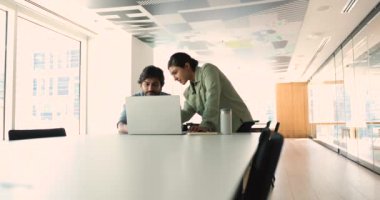 Hintli bayan lider proje detaylarını modern ofisteki bilgisayardaki meslektaşıyla tartışıyor. İşbirliği ve başarıya odaklan, dijital veri ve stratejiyi analiz et, iş hedeflerine ulaşmak için birlikte çalış