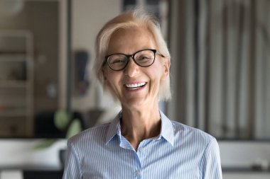 Gülümseyen yaşlı profesyonel kadın, günlük gömlekler giyen proje lideri, iş yerinde poz veren gözlük takan, liderlik, beceri, deneyim ve bilgelik saçan. Şirket portresi.
