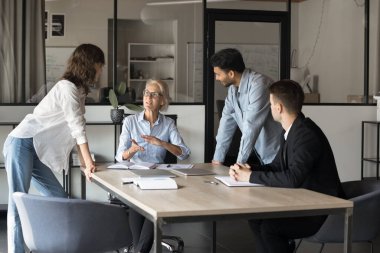 Orta yaşlı kadın profesyonel iş eğitmeni seminer ya da brifing vererek ilgili çok ırklı öğrencilerle konuştu. Şirket çalışanlarına kurumsal hedefler ya da yeni fikirler sunmak.